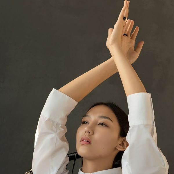Woman in a peaceful yoga pose against a dark, minimalist background.
